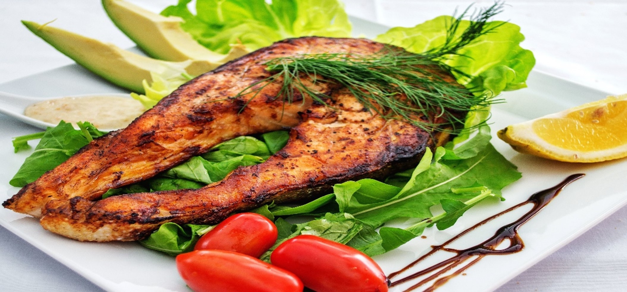 A plate with salmon, lettuce and tomatoes
